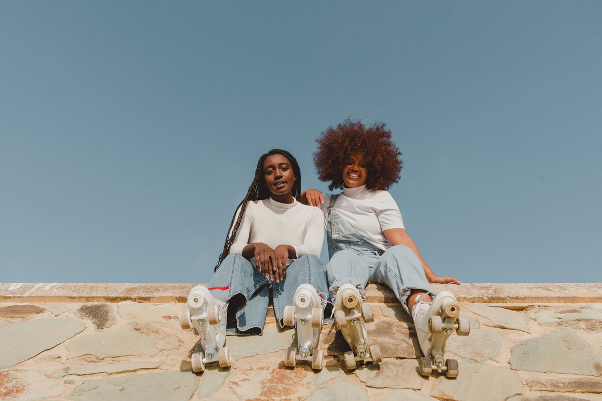 Two Female Friends in Roller Skates Sitting Outdoors