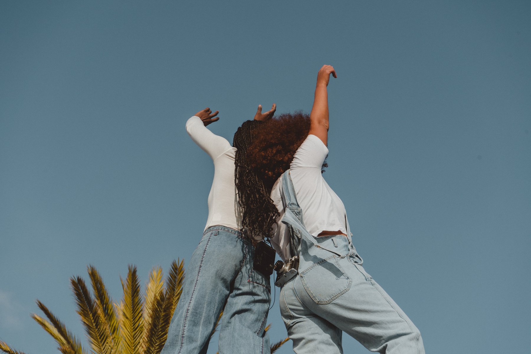 Two Carefree Teenage Girls Raising Hands in the Sky