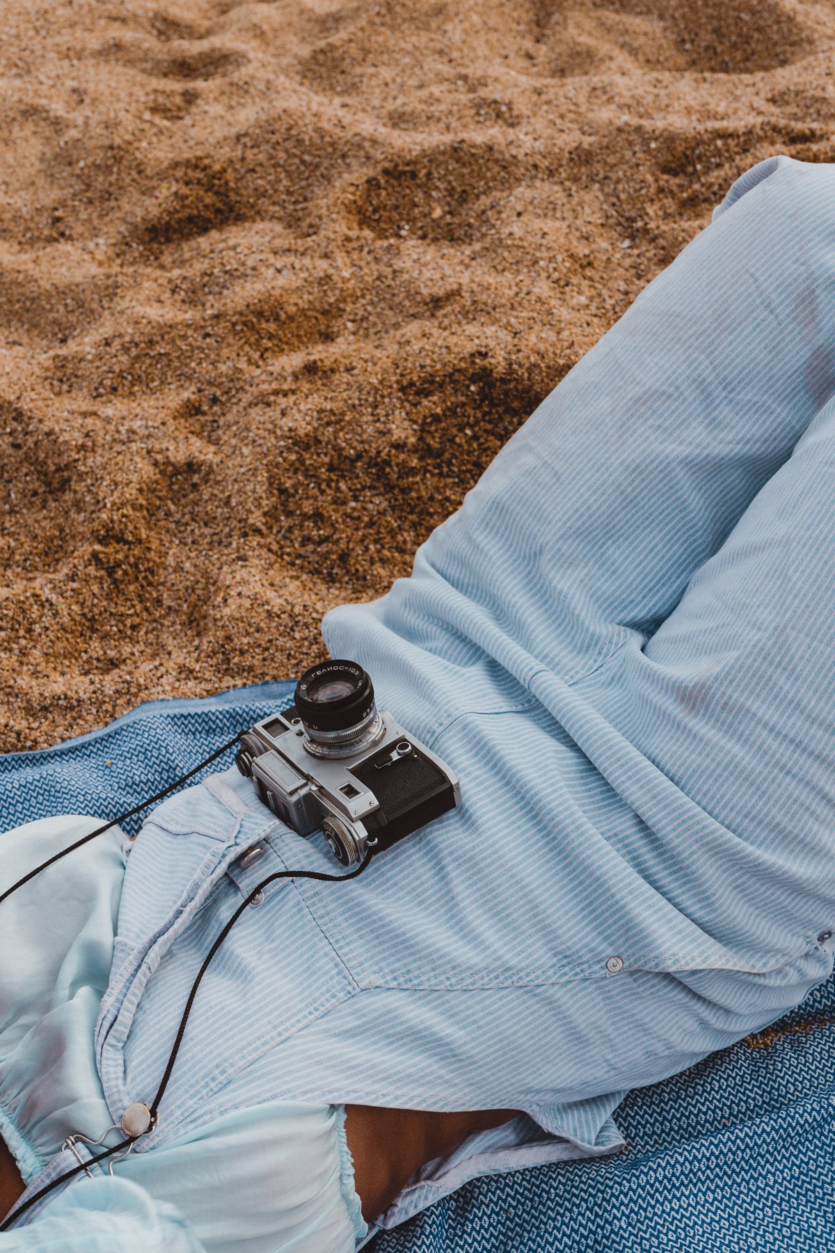 Woman with Retro Camera Lying on Sand